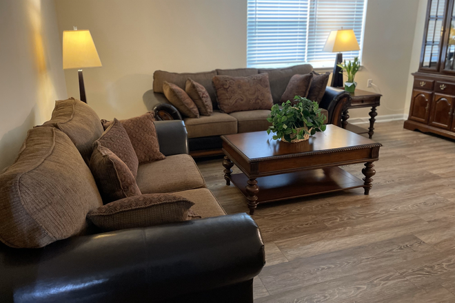 Sunlit living room with large window, cozy seating, and peaceful study vibes. - Affordable Housing – Easy Access to Loyola, John Hopkins Homewood, Morgan