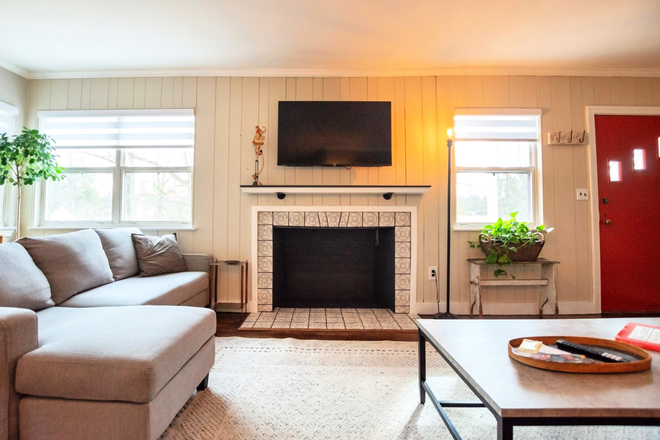 Expansive living room with decorative fireplace and multiple seating areas for watching tv or relaxing - Nature Retreat Close to Downtown House