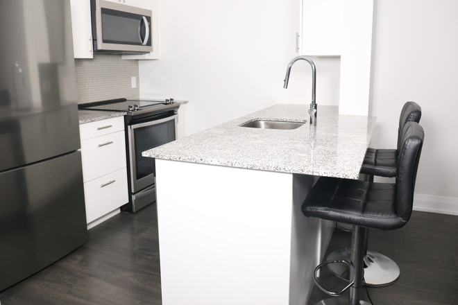 Kitchen area with stove, microwave, marble top counter, and two new barstools. - 1 Bedroom Apartment Fully Furnished Turnkey UofT UTSC OCMT
