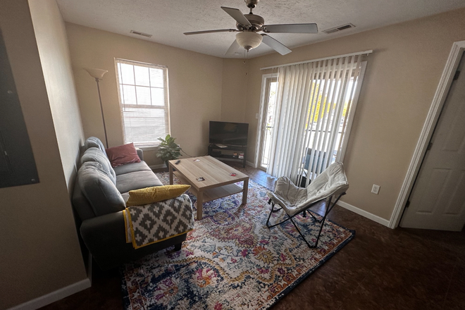 Living room with door to balcony shown - Evergreen Apartments