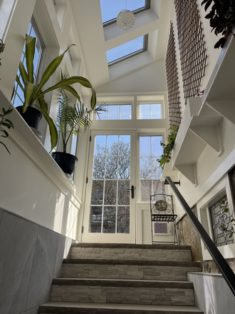 The garden entrance passes through a plant-filled sunroom. - Brand New, Light-Filled, Furnished 2BR, 1.5BA with Parking, Charger, W/D, In Brookline Victorian Apartments