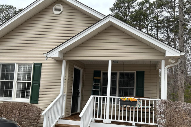 Front of House with porch swing - Four bedroom Home 10 min. from campus w/one basement suite w/private bath available as of 5/1/25