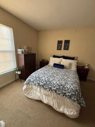 Bed, dresser, and left and right night stand, with hanging pictures - Mountaineer Village Apartments