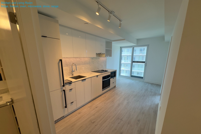 Kitchen and living room area towards the window - Modern 1-Bed+Den | Steps to St. Michael's Hospital, UofT, TMU | In-Suite Laundry