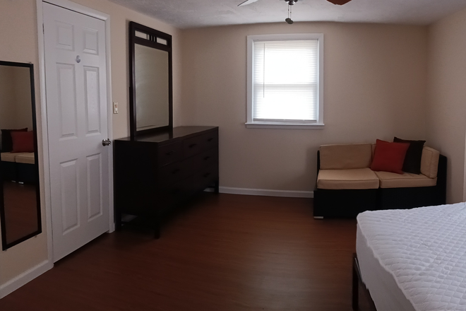 Large dresser with mirror, seating area, and full-size bed. - Short Walk to Hofstra